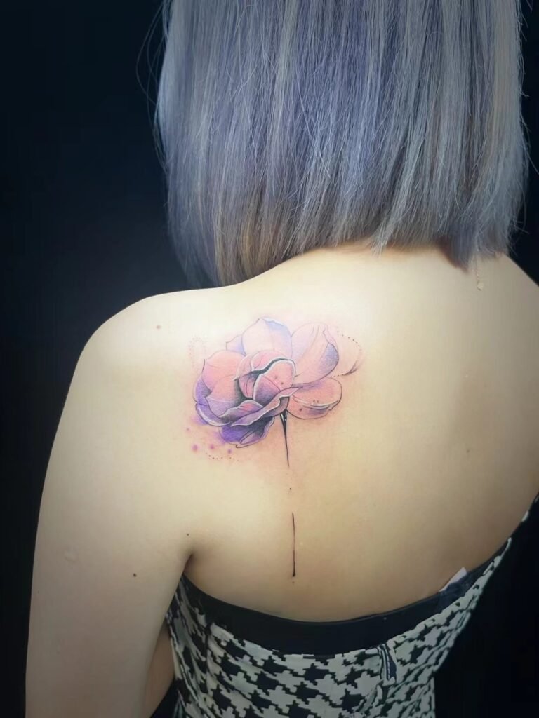 Single purple floral tattoo on the upper back
