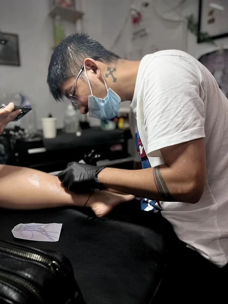 Tattoo artist working beside a leg placement sketch