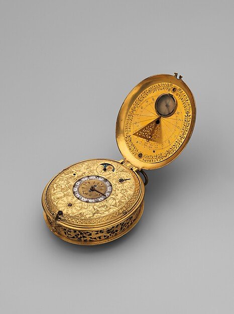Open gold clock watch with an astronomical dial and sundial on a grey background