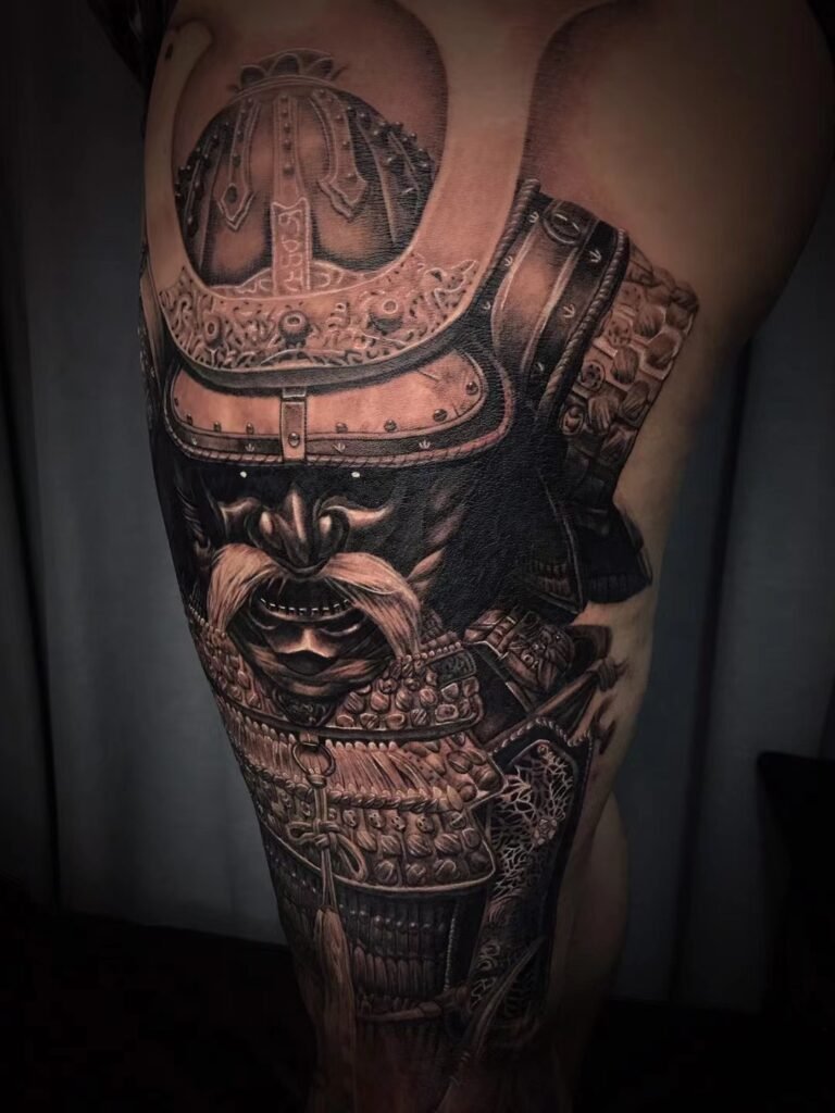 Angled view of an armoured helmet and face-mask tattoo on the thigh