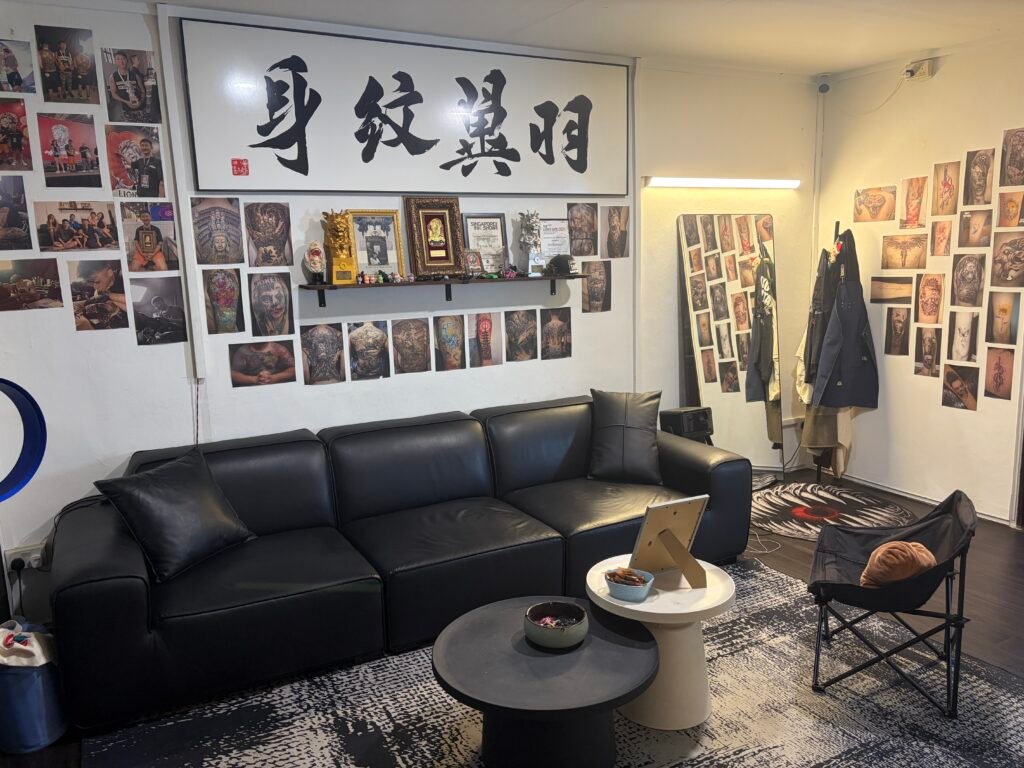 Waiting area at Yuyi Tattoo with dark seating, a round table and framed calligraphy