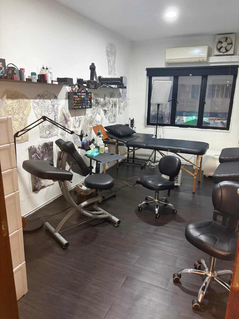 Tattoo room at Yuyi Tattoo with an adjustable bed, task lights and workstation chairs